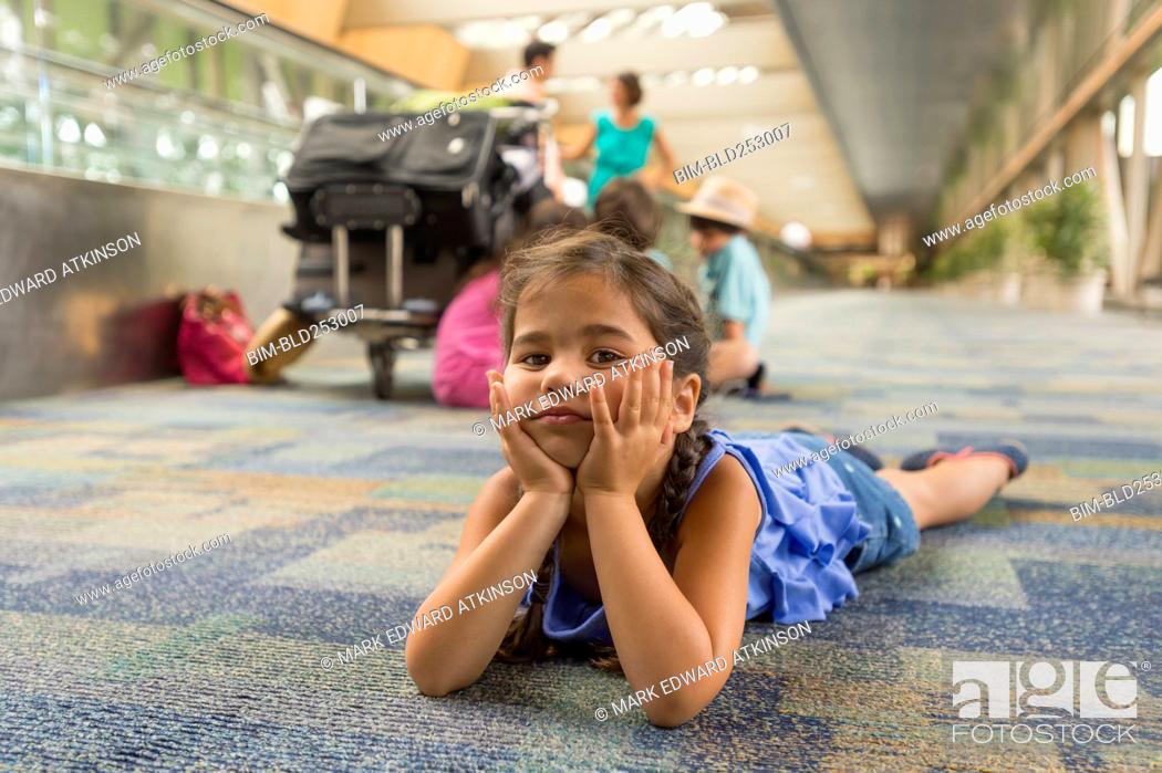 Stock Photo: Bored girl laying on floor of airport.
