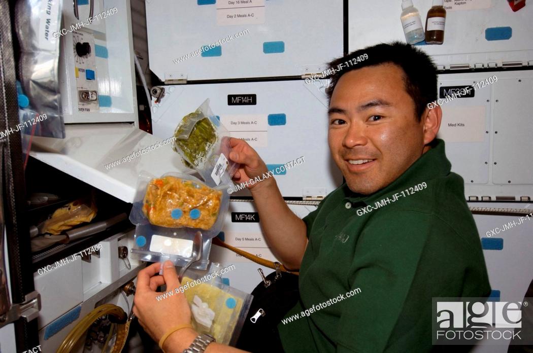 Stock Photo: Japan Aerospace Exploration Agency (JAXA) astronaut Akihiko Hoshide, STS-124 mission specialist, prepares to eat a meal at the galley on the middeck of Space.