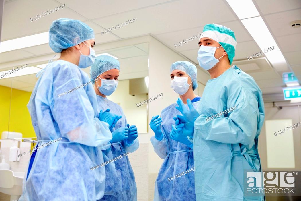 Stock Photo: surgery, medicine and people concept - group of surgeons in operating room at hospital talking and preparing to operation.