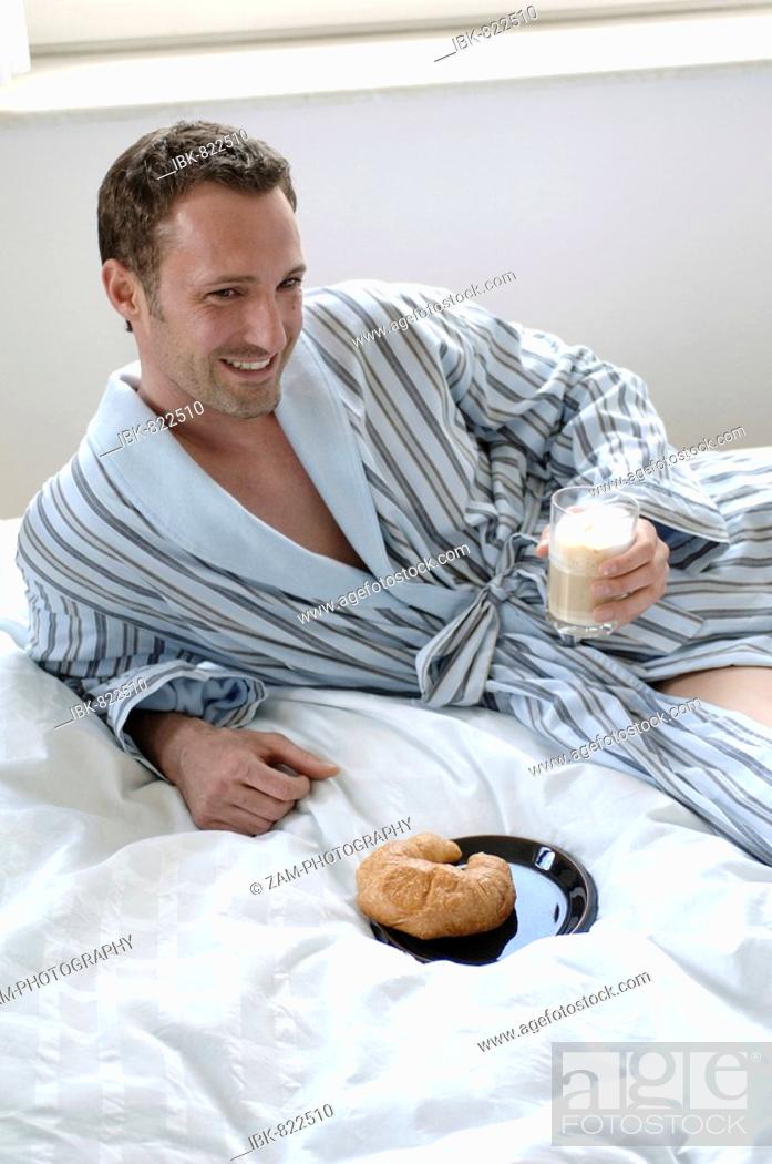 Happy young man in dressing gown drinking martini Stock Photo by ©lofilolo  30954309