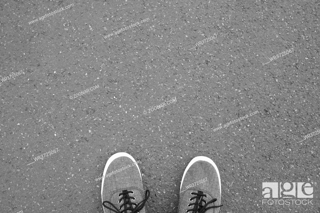 Stock Photo: feet in canvas shoes standing on street - foot selfie from personal perspective point of view - asphalt background with copy space.