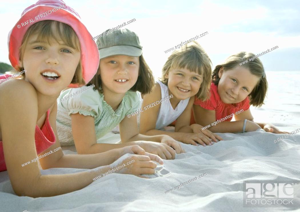 Imagen: Four girls lying on beach, smiling at camera, close-up.