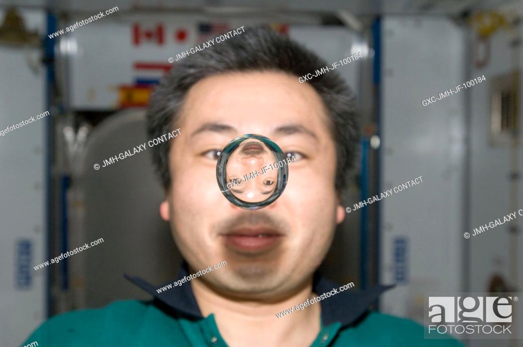 Stock Photo: Japan Aerospace Exploration Agency (JAXA) astronaut Koichi Wakata, Expedition 20 flight engineer, watches a water bubble float freely between him and the camera.