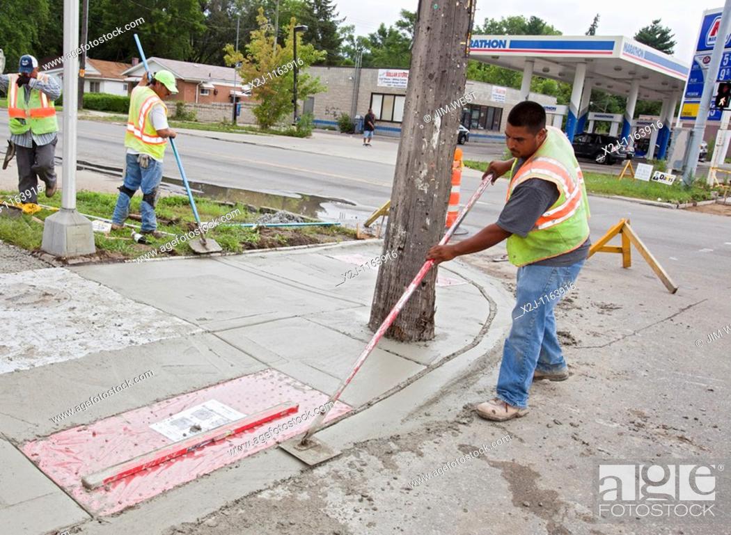 Stock Photo: Detroit, Michigan - Workers install a curb ramp at a street intersection to allow access for people with disabilities  The ramps are required by the Americans.