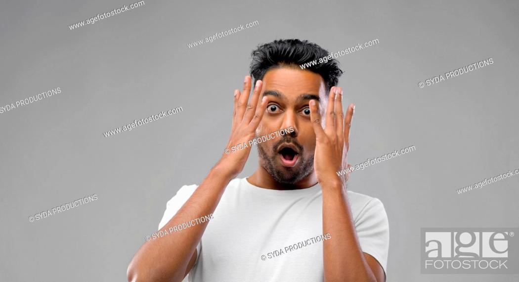 Stock Photo: shocked indian man over grey background.