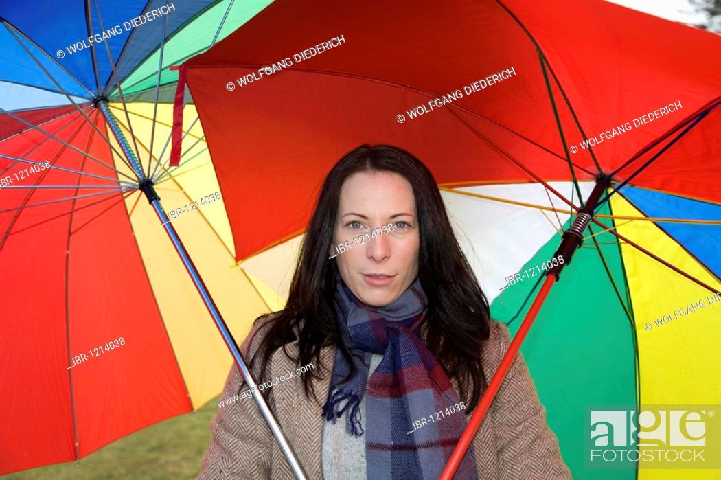 Stock Photo: Young woman, 30-35 years, protecting herself with two colorful umbrellas against the cold winter weather.