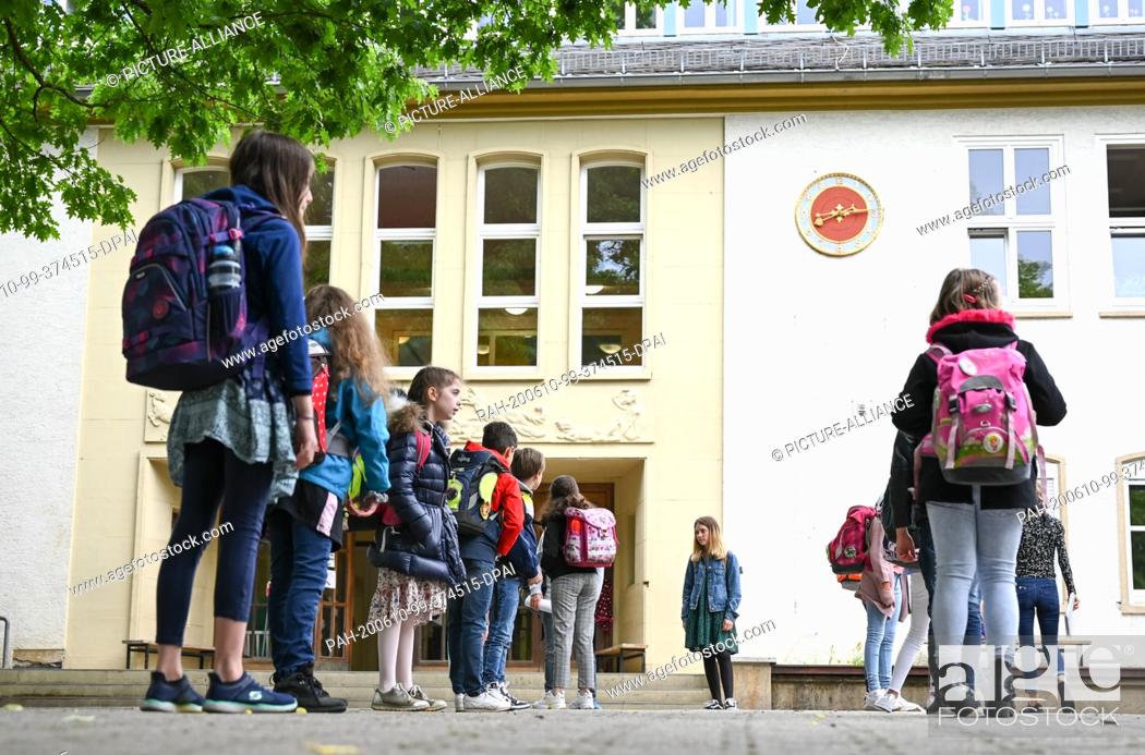 Stock Photo: 10 June 2020, Hessen, Wiesbaden: Pupils of the fourth grade of the Robert Schumann Primary School stand in front of the classroom in the schoolyard.