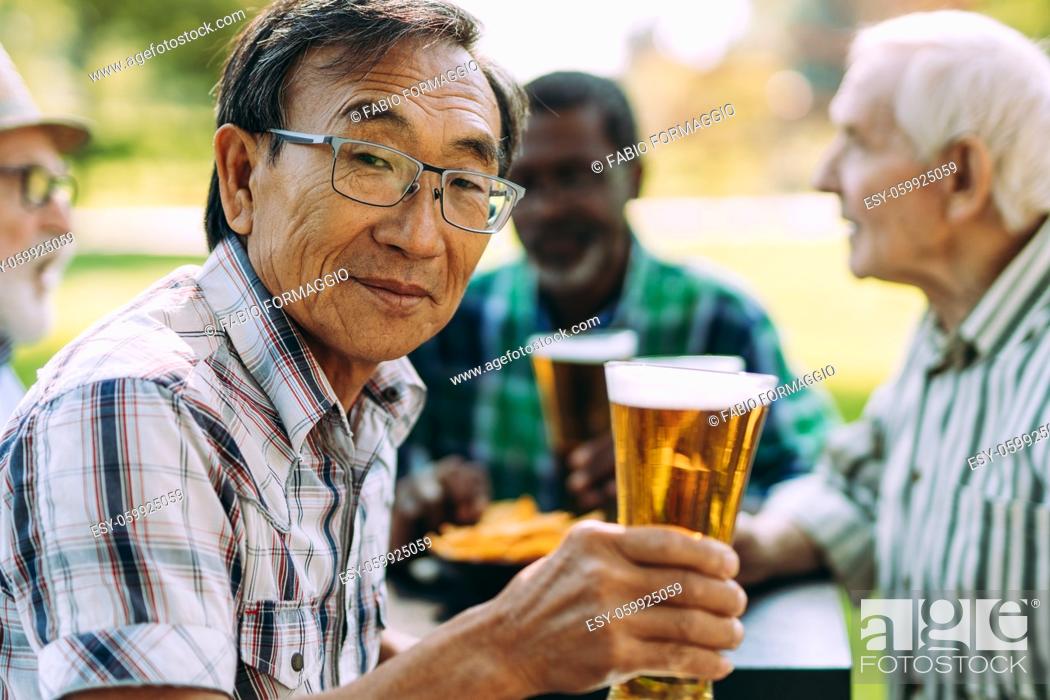 Stock Photo: group of senior friends drinking a beer at the park. Lifestyle concepts about seniority and third age.