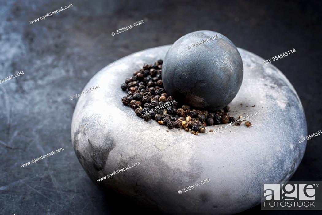 Stock Photo: Modern design minimalistic mortar with black pepper berries as closeup on a rustic board with copy space left.