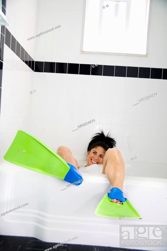 Stock Photo: Woman wearing flippers in bathtub.