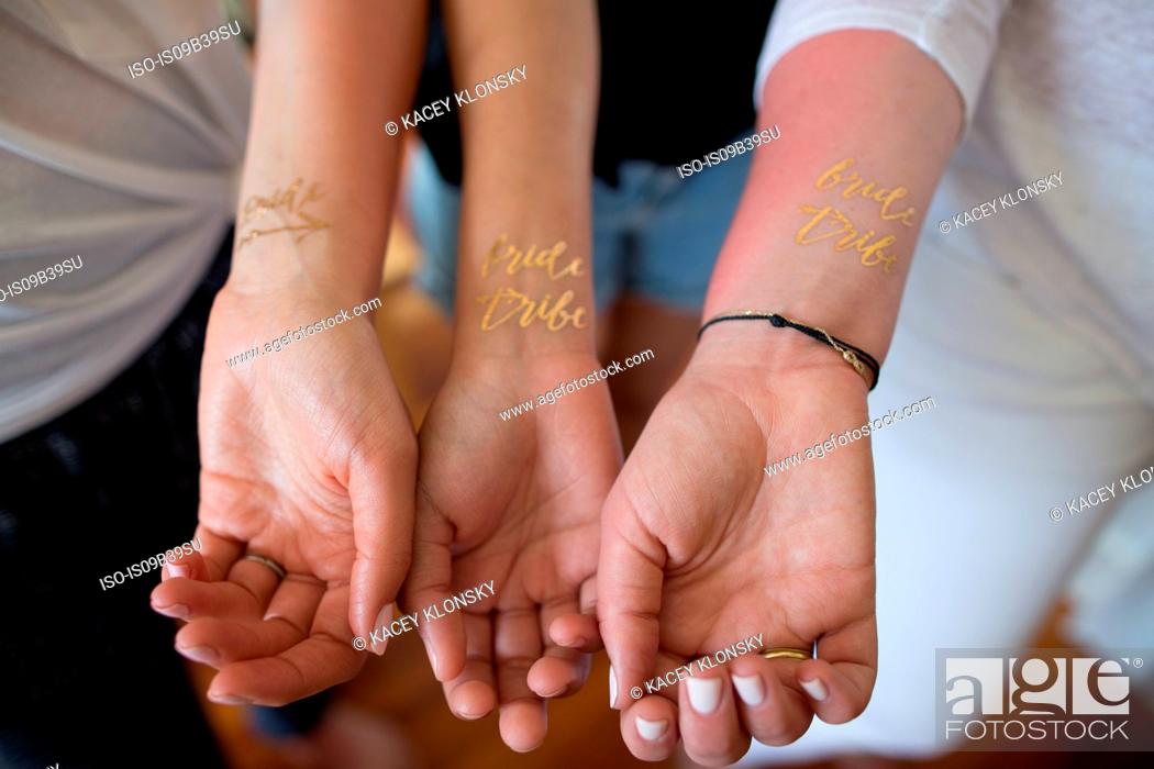 Three young women showing temporary 'Bride tribe' tattoos on wrists,  close-up, Stock Photo, Picture And Royalty Free Image. Pic. ISO-IS09B39SU |  agefotostock