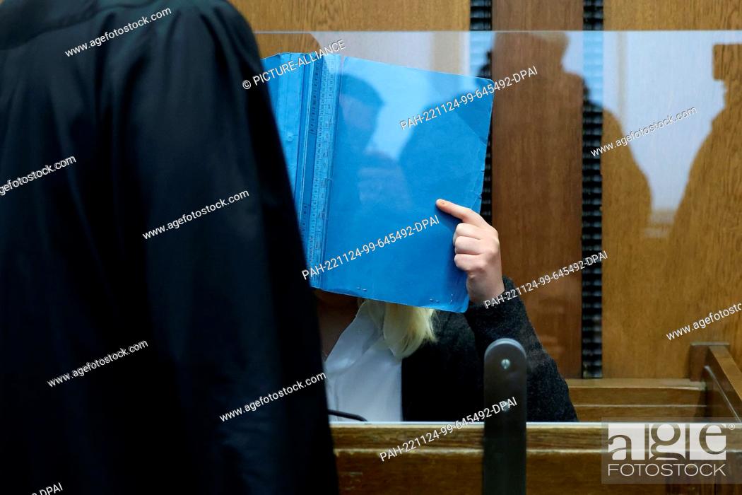 Stock Photo: 24 November 2022, North Rhine-Westphalia, Mönchengladbach: The defendant covers her face with a blue folder in the regional court.