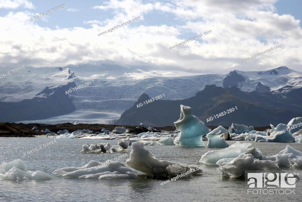 Stock Photo: A stunning landscape of a lagoon in Iceland, with the ice cold water and small icebergs, and snowy mountains in the background.