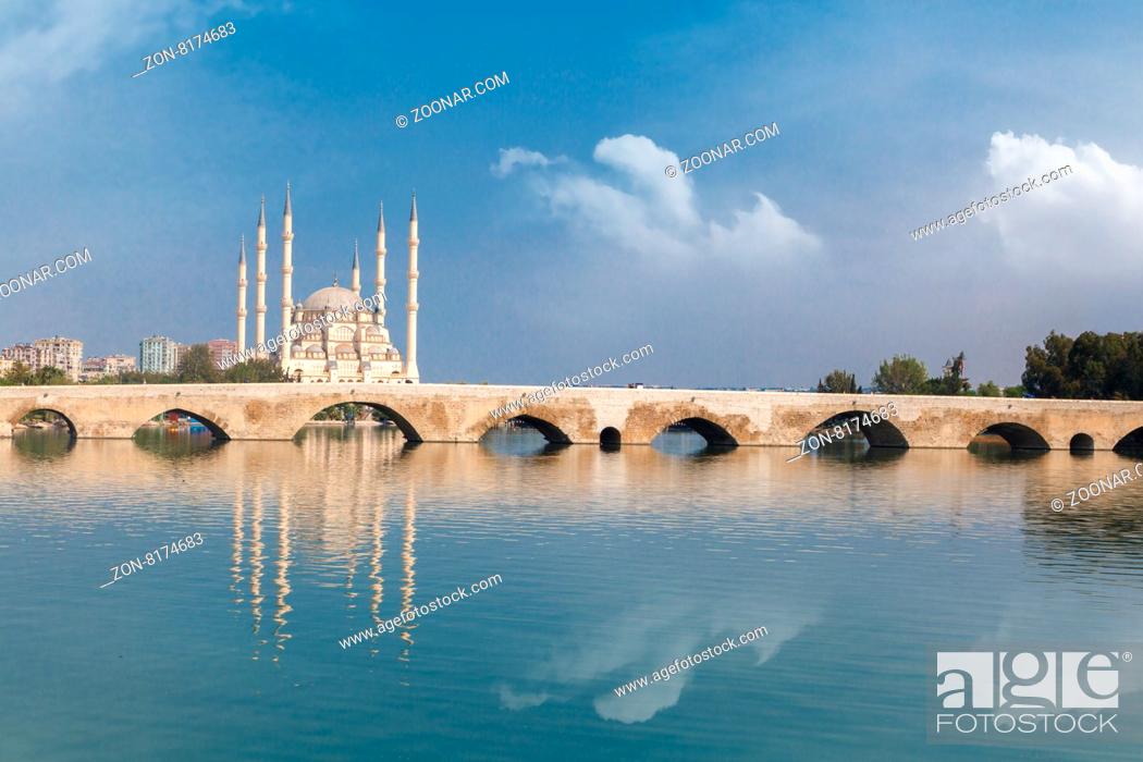 Stock Photo: Side view of historical old stone bridge of Adana on Seyhan river, on cloudy blue sky background.