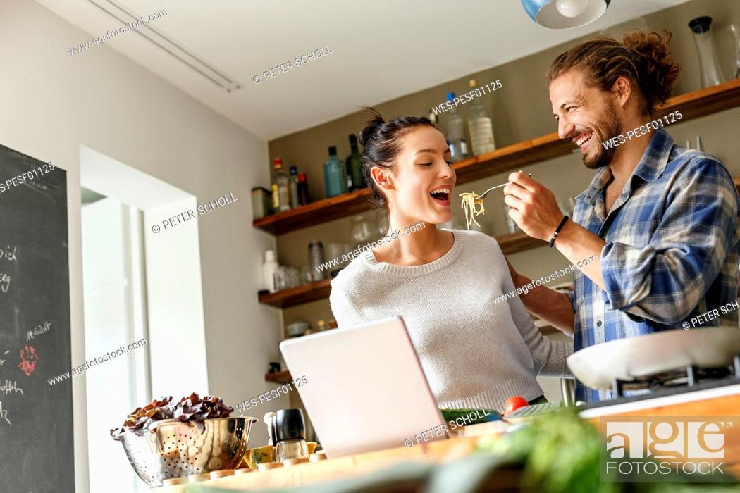 Stock Photo: Young couple preparing spaghetti together, using online recipe.