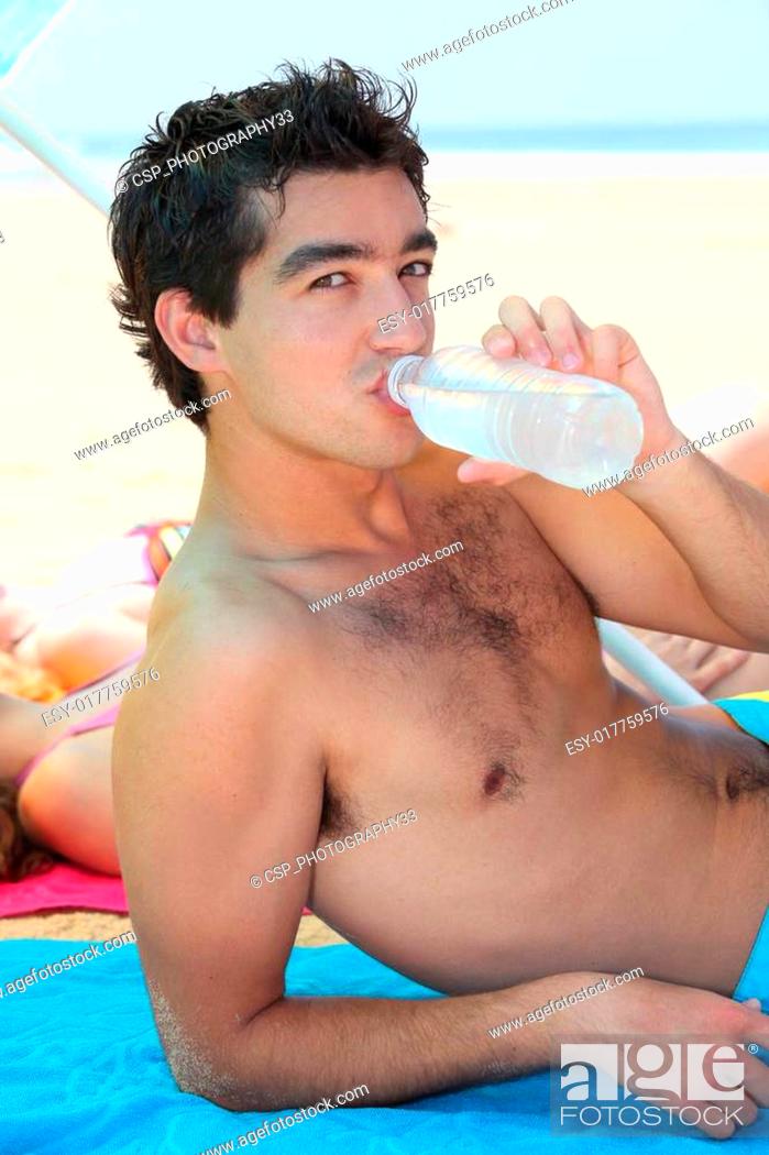 Stock Photo: Teenager drinking water on the beach.