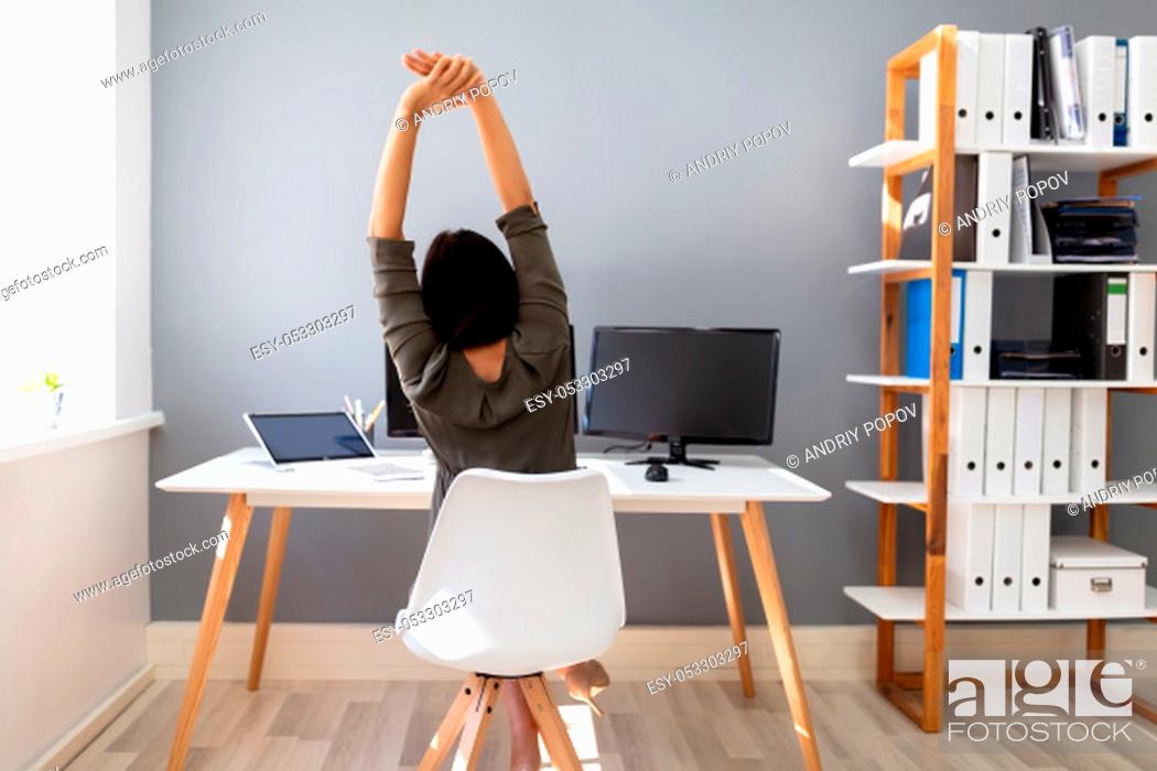 Stock Photo: Rear View Of Young Businesswoman Stretching Her Arms In Office.