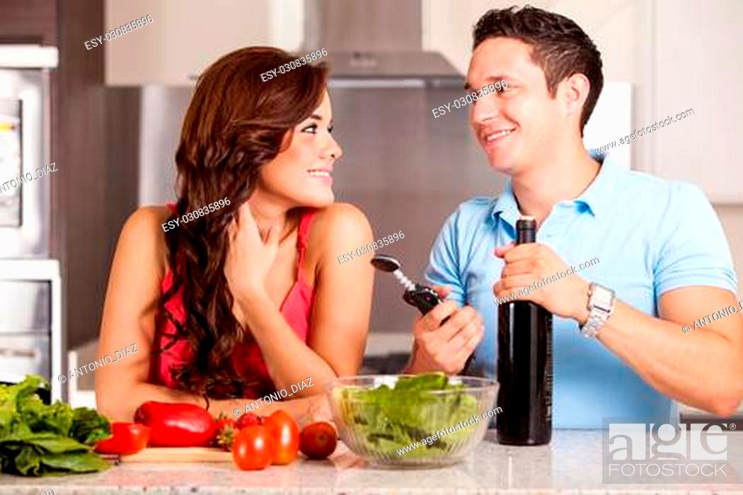Stock Photo: Happy brunette and her boyfriend cooking dinner and about to open a bottle of wine.