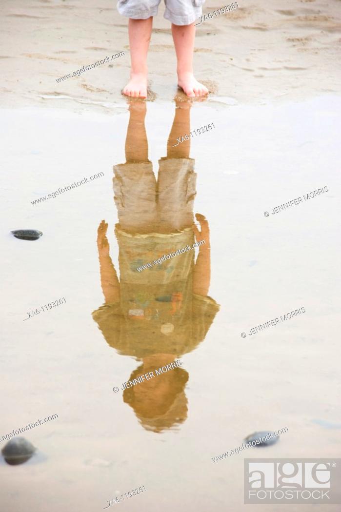 Stock Photo: A boy's legs and his reflection in a puddle on the beach.
