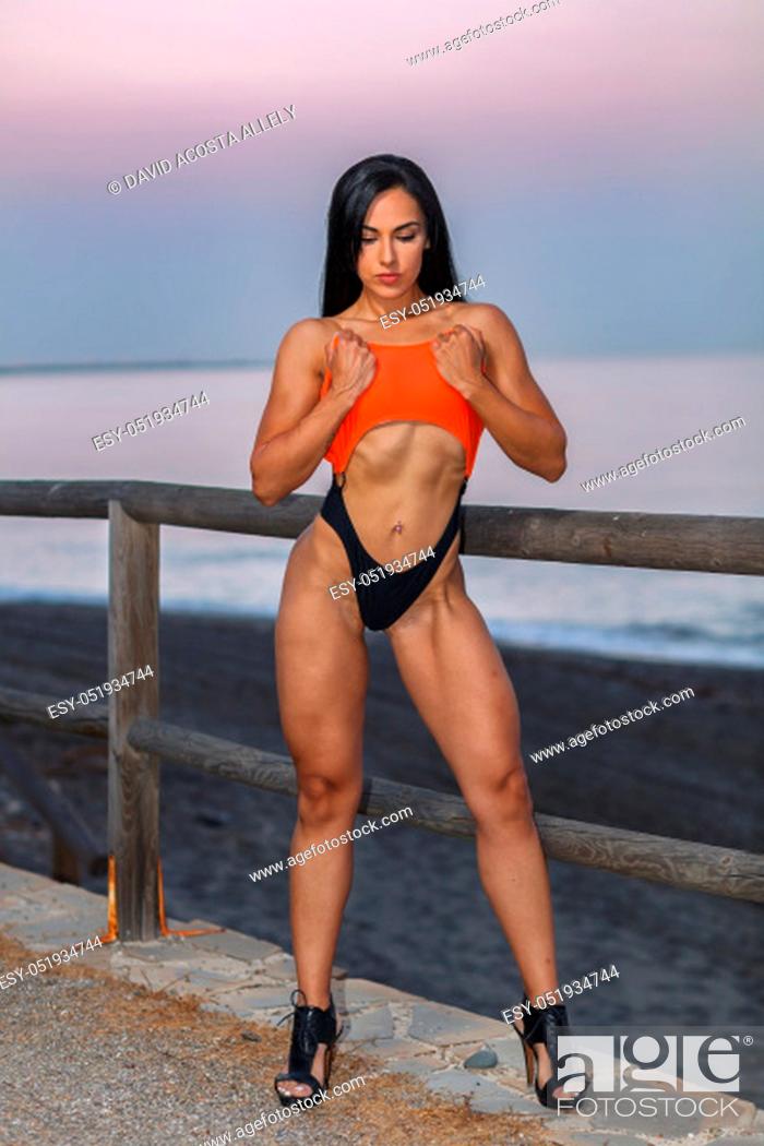 Stock Photo: Fitness girl posing in the beach with a beautiful black and orange bikini.