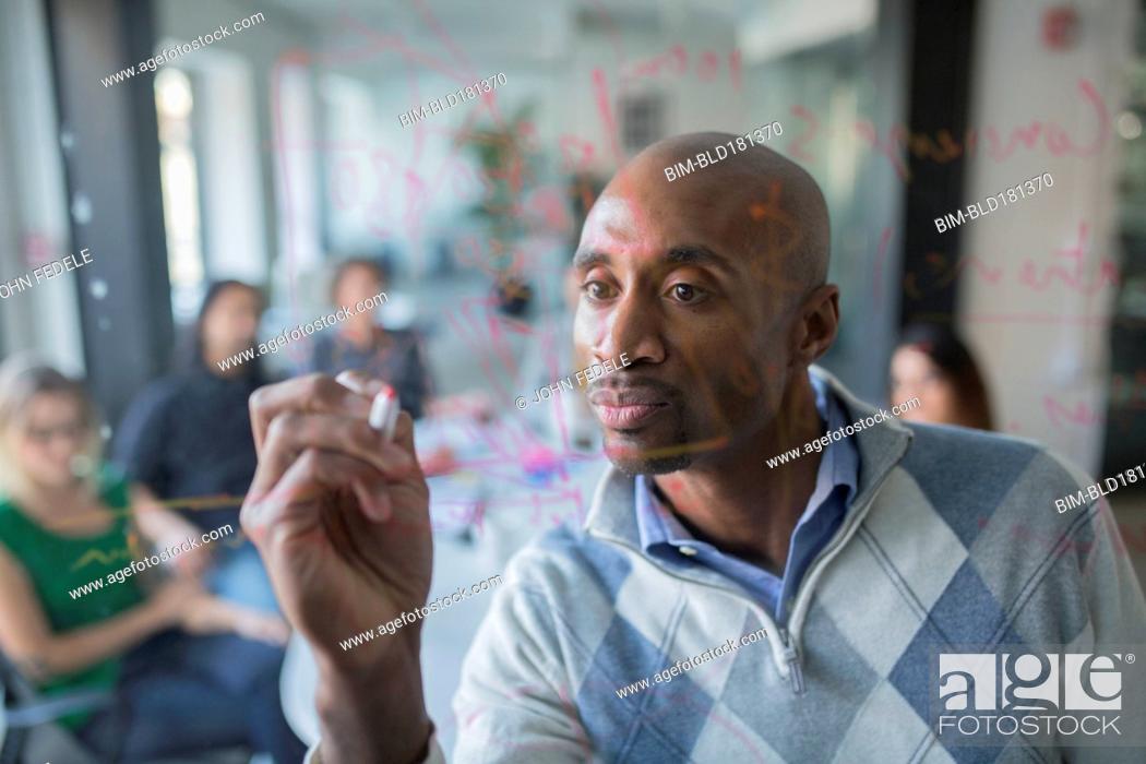 Stock Photo: Businessman drawing graph on glass wall in office.