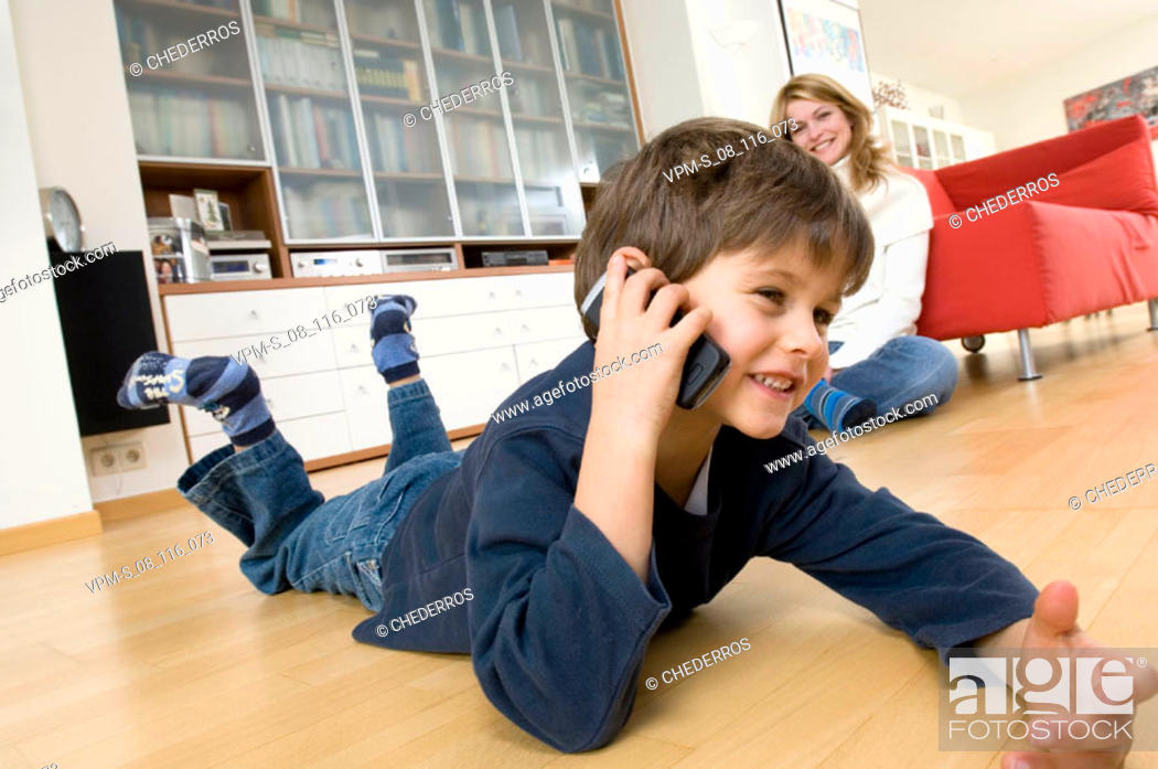 Stock Photo: Side profile of a boy using a mobile phone with his mother sitting beside him.