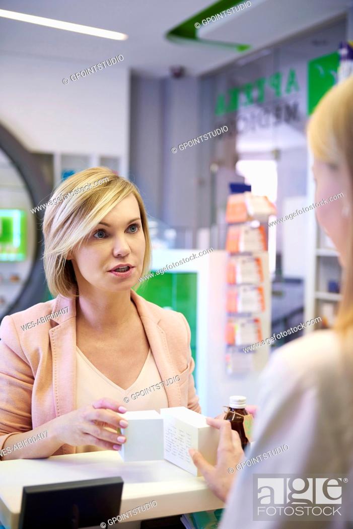 Stock Photo: Woman discussing product with pharmacist in pharmacy.