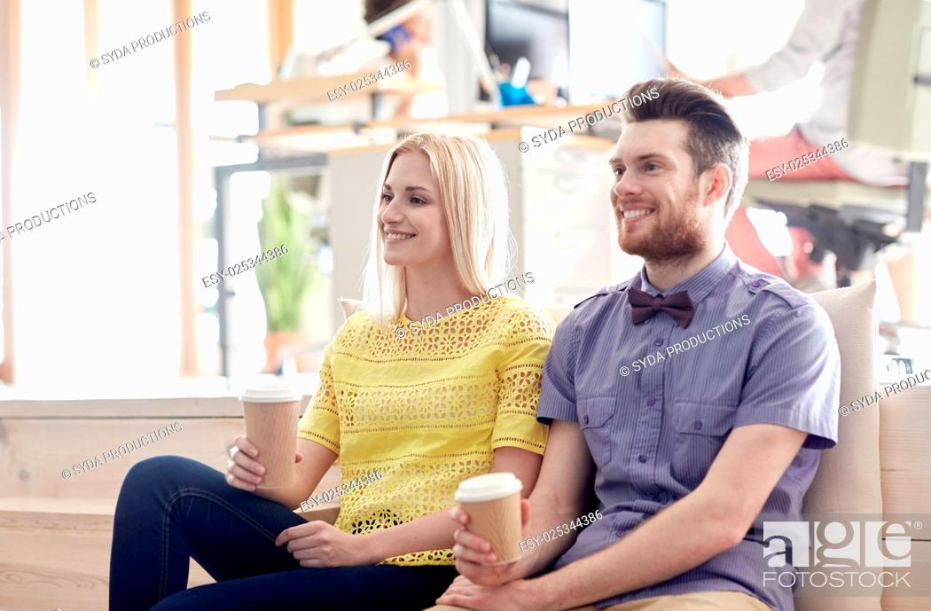 Stock Photo: business, startup, people and communication concept - happy man and woman drinking coffee in office.