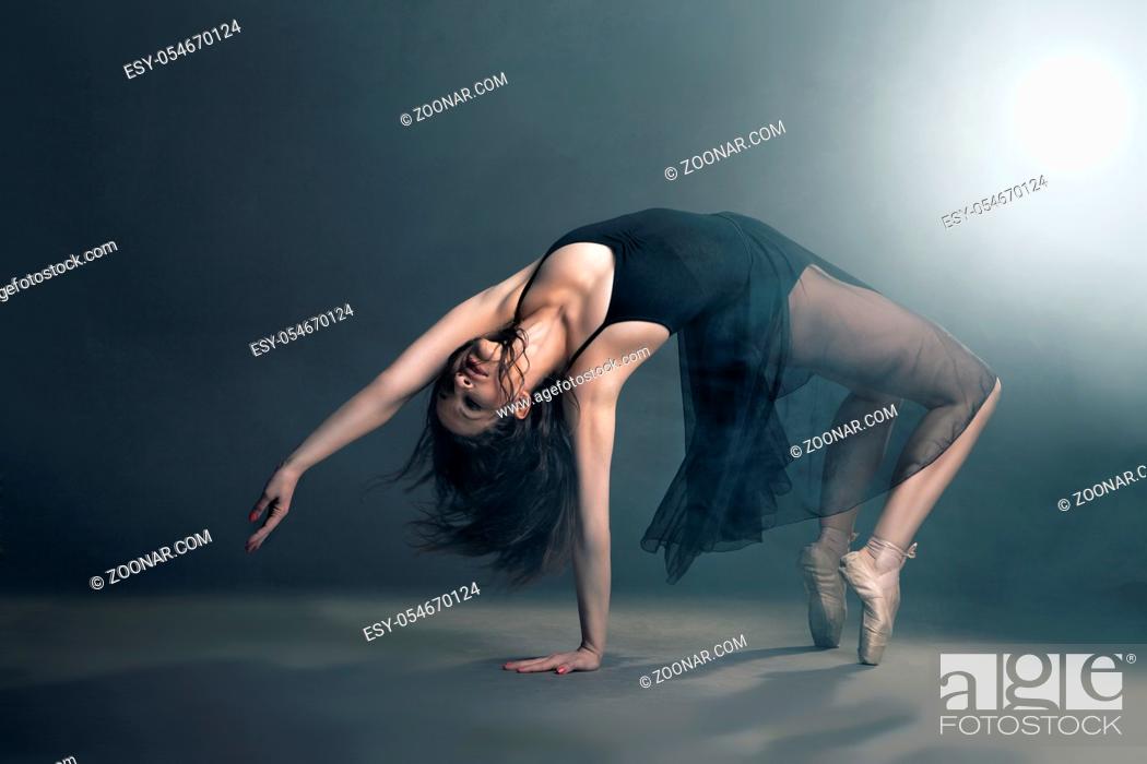 Stock Photo: Modern style dancer posing on a studio grey background in fog.
