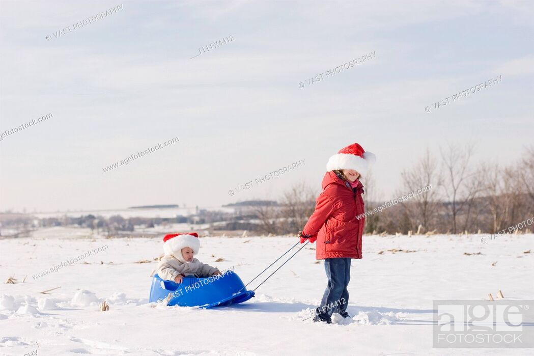 Stock Photo: Sister Pulling her Brother through Snow on Sled.