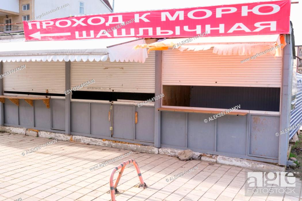 Stock Photo: Closed trade pavilions with a banner, a passage to the sea and barbecue, on a deserted seaside street.