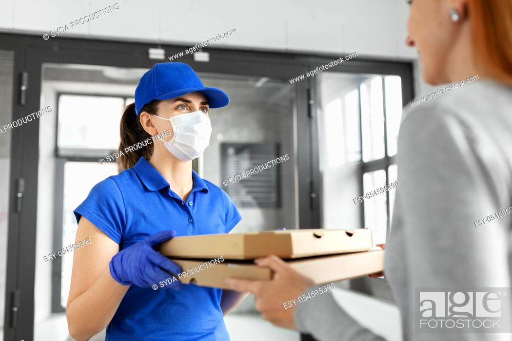 Stock Photo: delivery girl in mask giving pizza boxes to woman.