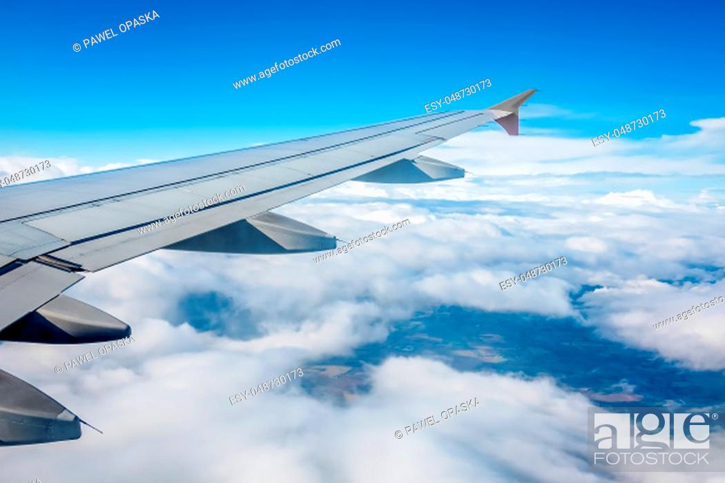 Stock Photo: Window view of the wing of an airplane flying above the clouds.