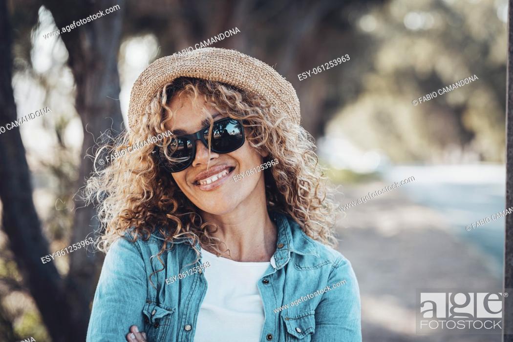 Photo de stock: Portrait of young adult woman smiling at the camera with sunglasses and straw hat. Female people happy in outdoors leisure activity.
