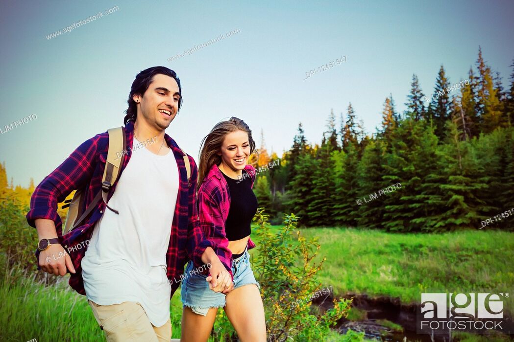 Stock Photo: Young couple running while holding hands in a city park in autumn; Edmonton, Alberta, Canada.