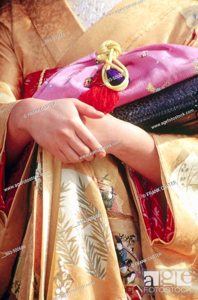 Stock Photo: A view of a Geisha on the temple grounds of Nanzenji showing her kimono with hands clasped around her traditional hand bag. Kyoto city.  Kyoto. Japan.