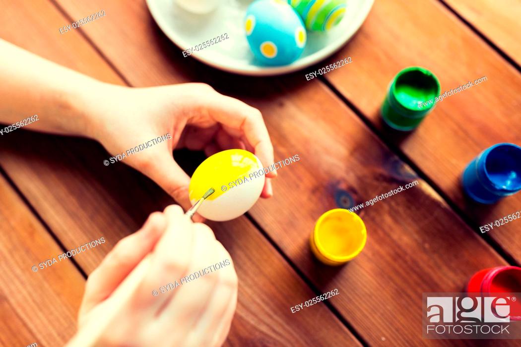 Photo de stock: easter, holidays, tradition and people concept - close up of woman hands coloring easter eggs with colors and brush.