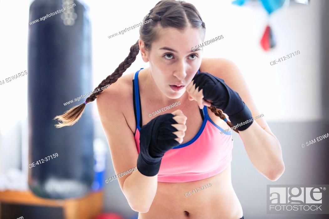 Imagen: Determined, tough young female boxer shadowboxing in gym.