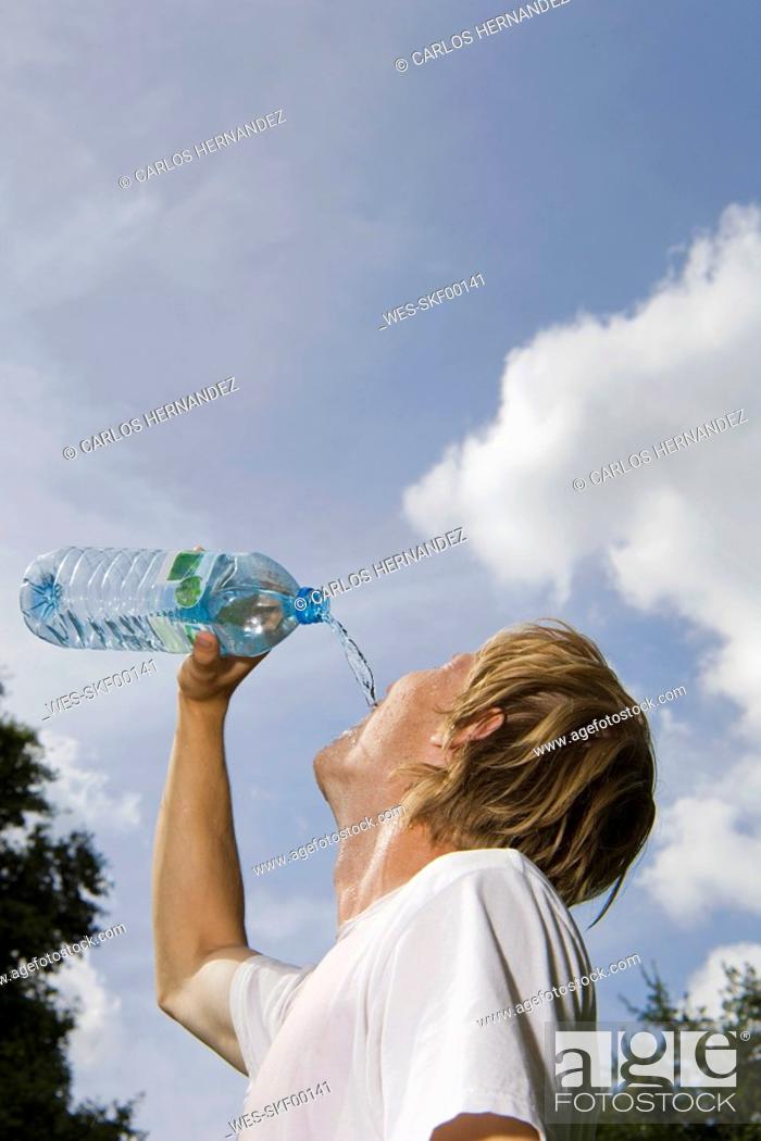 Stock Photo: Germany, Berlin, Young man drinking from water bottle, portrait.