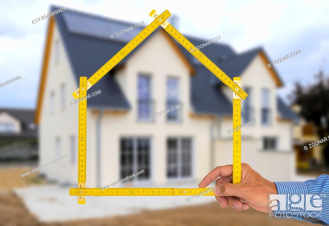Stock Photo: yardstick folded in form of an house in hand of an agent.