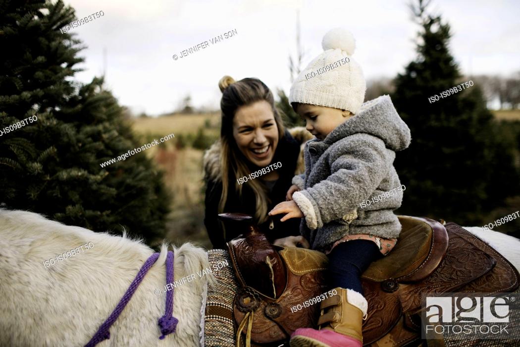 Stock Photo: Mother smiling at baby girl riding on horse.