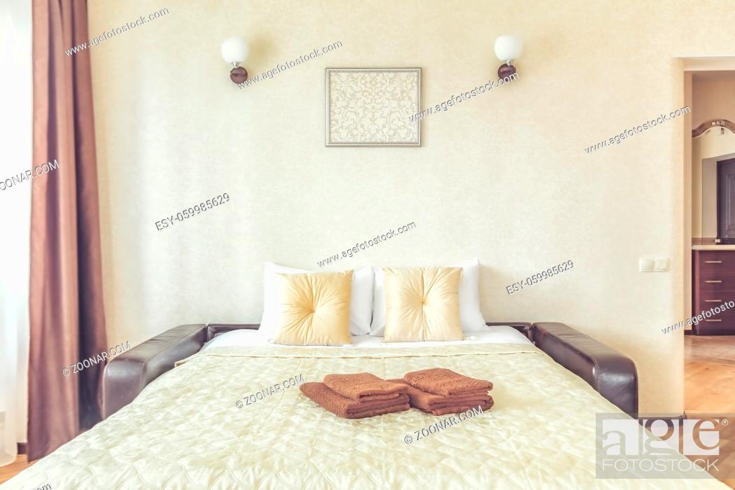 Stock Photo: pillow on bed and nightstand in cozy comfortable bedroom in beige color.
