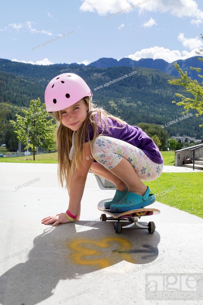 Stock Photo: Young girl on a skateboard wearing a pink helmet; Salmon Arm, British Columbia, Canada.