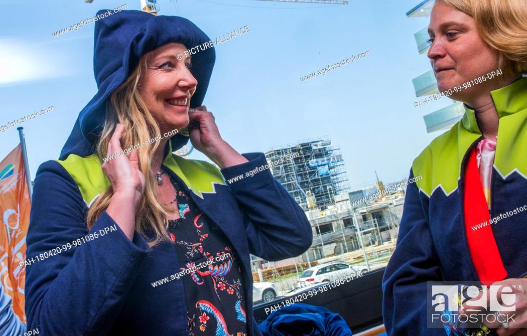 Stock Photo: 20 April 2018, Germany, Rostock: Fashion designer Jette Joop (l) tries on a hat from the winning design at the competition ""Trachten neu erleben"".