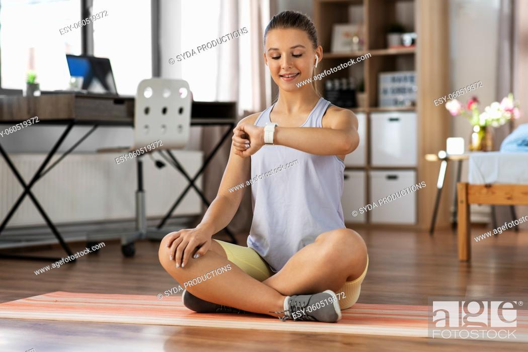 Stock Photo: teenage girl with gadgets exercising at home.