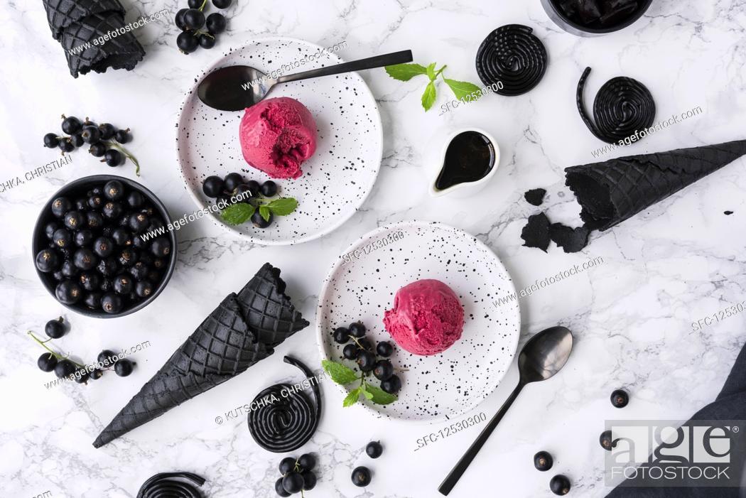 Stock Photo: Liquorice ice cream with blackcurrants on white dessert plates.