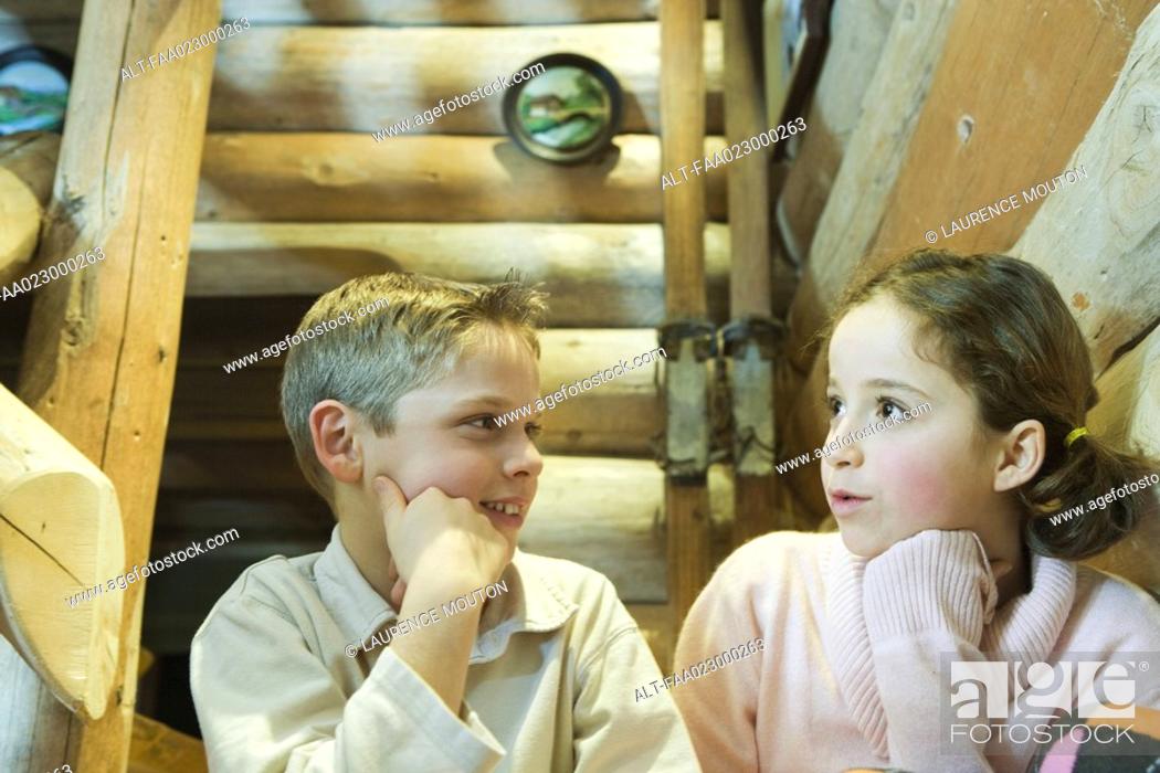 Stock Photo: Preteen boy and girl sitting side by side, talking.