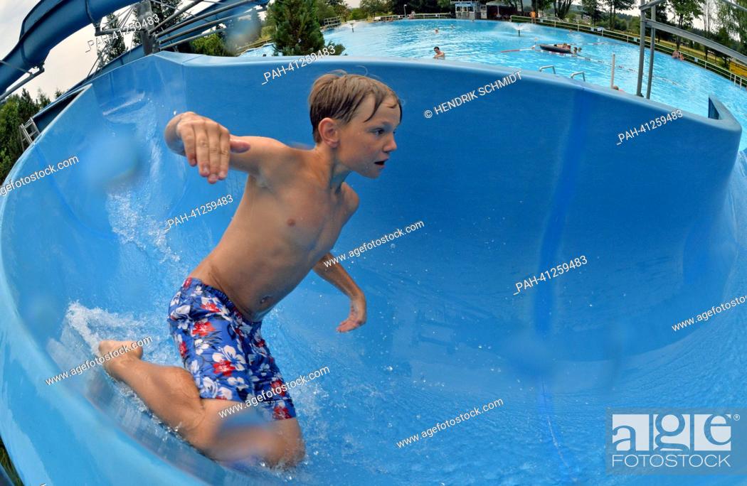 Stock Photo: A boy slides into the water on the 75 m long waterslide in the bath of Rebesgruen, Germany, 24 July 2013. This weekend the 17th German water sliding.
