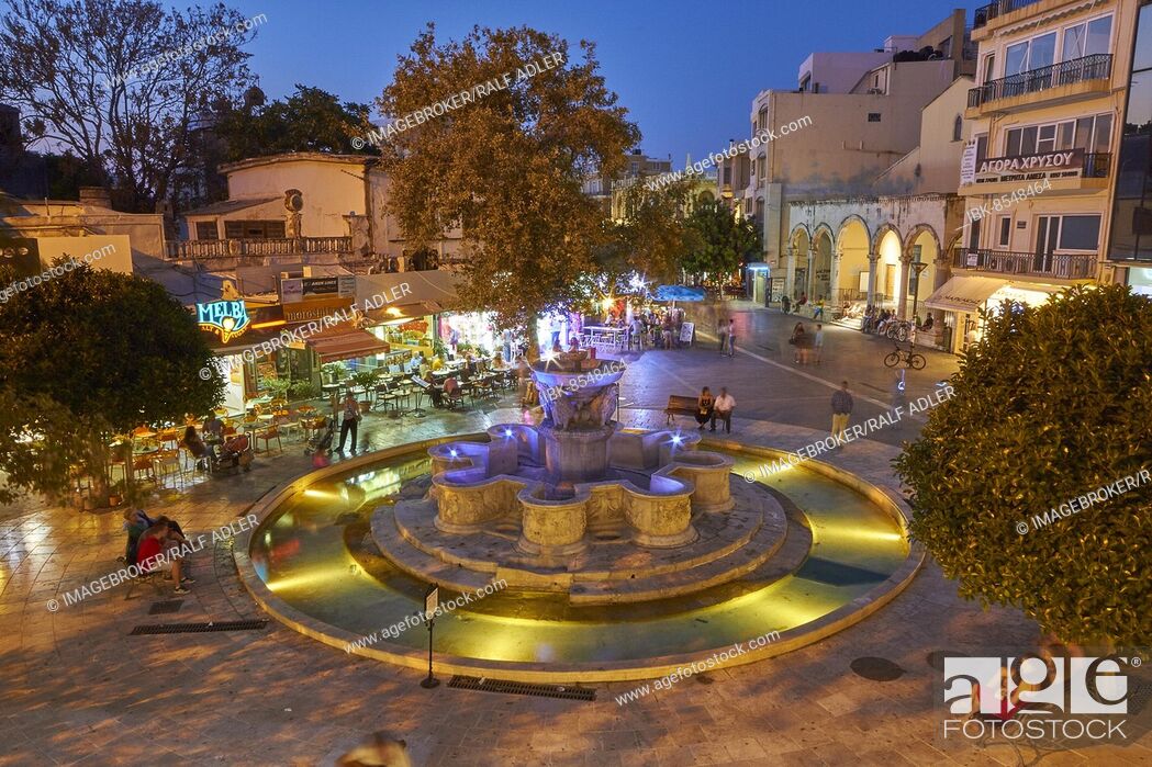 Stock Photo: Night shot, blue evening sky, artificial lighting, Venetian Morosini Fountain, super wide angle, passers-by, downtown, old town, Heraklion, capital.