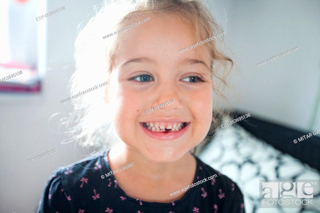 Stock Photo: Portrait of cute smiling little girl showing dropped first milk tooth at home.